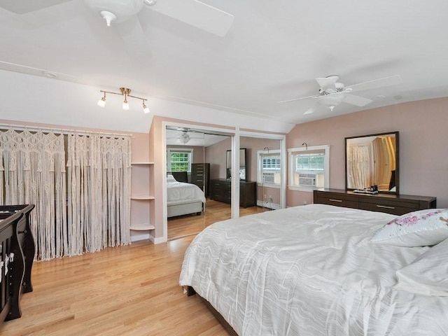 bedroom with ceiling fan, cooling unit, light wood-type flooring, and vaulted ceiling