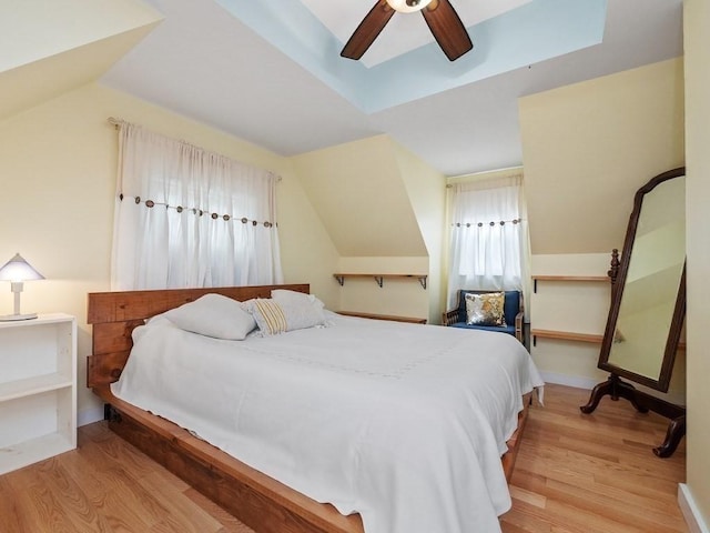 bedroom featuring light hardwood / wood-style floors, vaulted ceiling, and ceiling fan