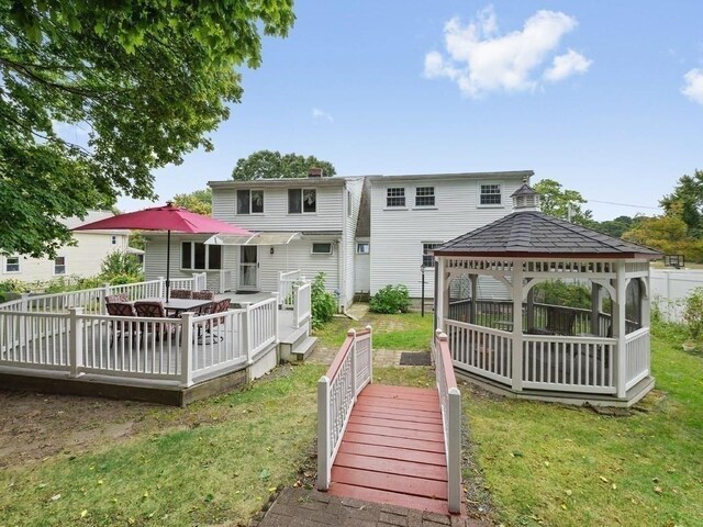 back of house with a gazebo, a wooden deck, and a lawn