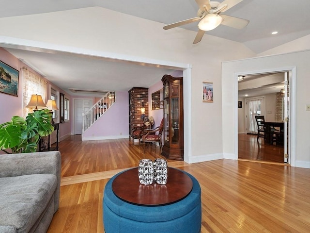 living room with ceiling fan, hardwood / wood-style floors, and vaulted ceiling