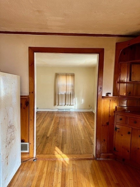 corridor with crown molding, light hardwood / wood-style flooring, and a textured ceiling