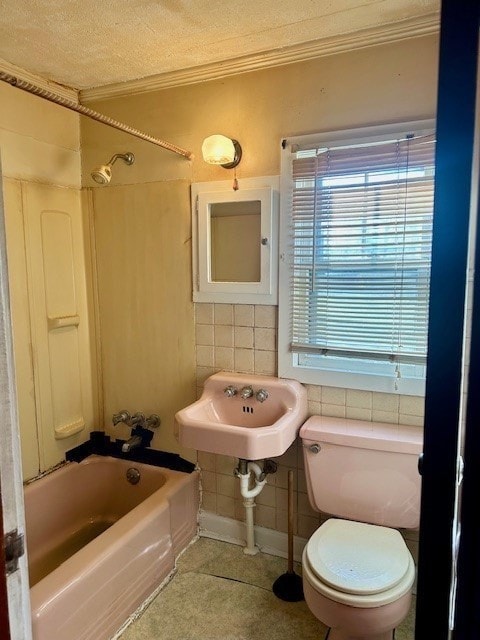 full bathroom featuring sink, a textured ceiling, toilet, shower / washtub combination, and tile walls