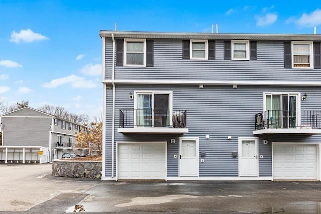 view of front of home featuring a garage, a balcony, and driveway