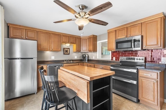 kitchen with a breakfast bar, wood counters, a center island, stainless steel appliances, and light tile patterned floors