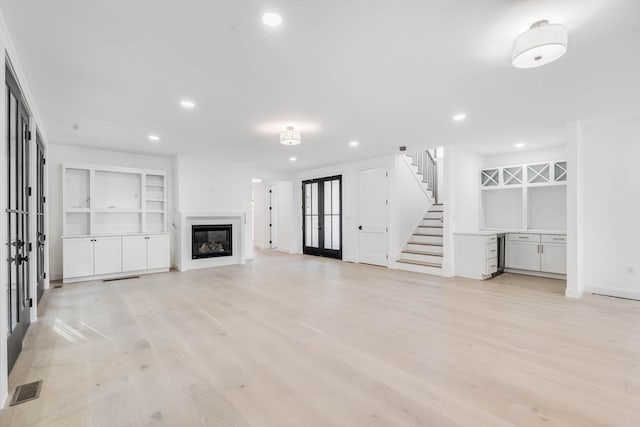 unfurnished living room featuring french doors and light hardwood / wood-style flooring