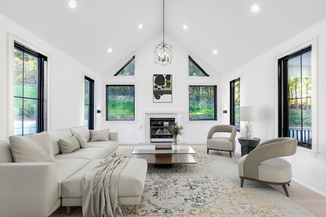 living room with a notable chandelier, light hardwood / wood-style floors, and high vaulted ceiling