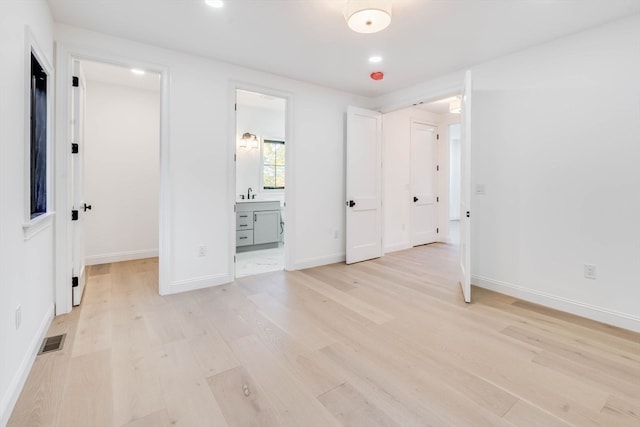 unfurnished bedroom with ensuite bath and light hardwood / wood-style floors