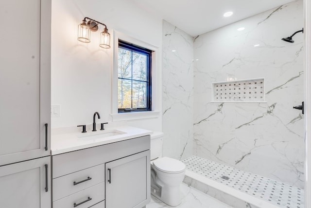 bathroom with vanity, tiled shower, and toilet