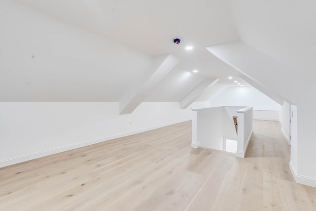 additional living space with light hardwood / wood-style flooring and lofted ceiling