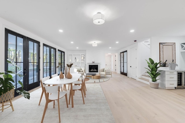 dining area with wine cooler, french doors, and light hardwood / wood-style flooring