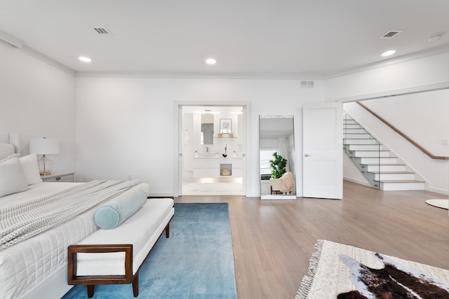 bedroom featuring wood-type flooring, crown molding, and ensuite bathroom