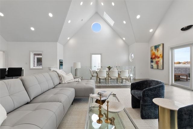 living room featuring light wood-type flooring, a skylight, and high vaulted ceiling