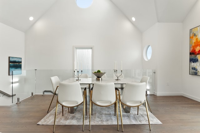 dining area with hardwood / wood-style floors and high vaulted ceiling