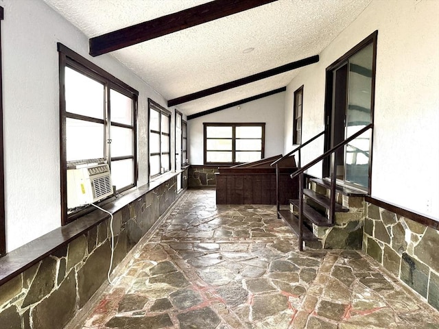 corridor featuring cooling unit, a textured ceiling, and vaulted ceiling with beams