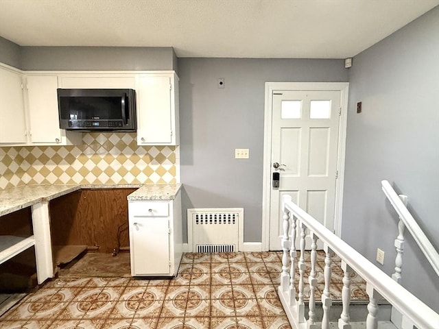 kitchen featuring radiator, light tile patterned floors, white cabinets, and light stone counters