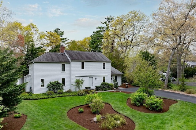 back of property with a yard, a chimney, and roof with shingles