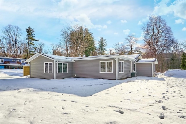 snow covered rear of property featuring central AC unit