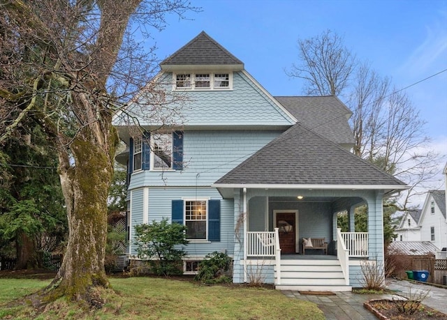 view of front of property with a porch, a front lawn, and roof with shingles