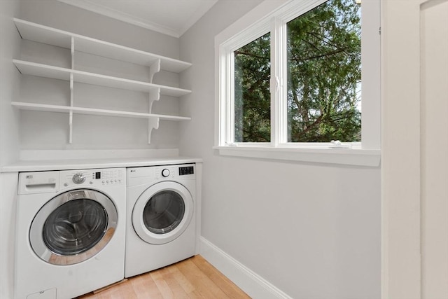 laundry area with baseboards, light wood finished floors, separate washer and dryer, and laundry area