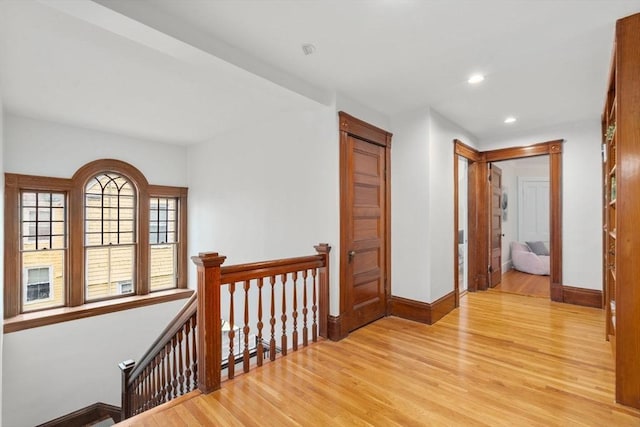 corridor featuring recessed lighting, light wood-style flooring, an upstairs landing, and baseboards
