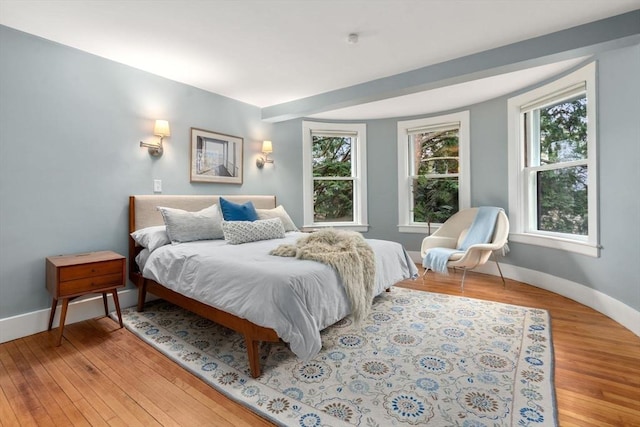 bedroom with baseboards, multiple windows, and hardwood / wood-style floors