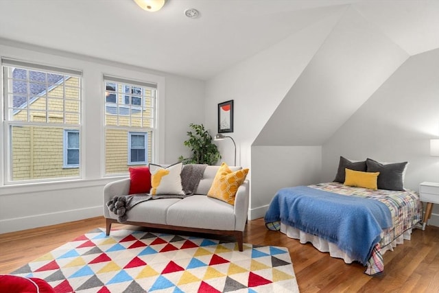 bedroom with wood finished floors, baseboards, and vaulted ceiling