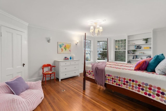 bedroom featuring a notable chandelier, baseboards, crown molding, and wood finished floors