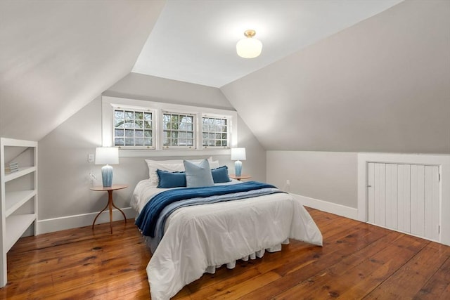 bedroom with wood-type flooring, baseboards, and lofted ceiling