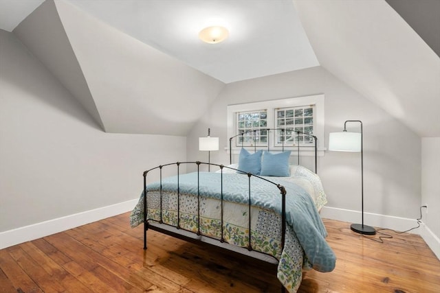 bedroom with baseboards, vaulted ceiling, and hardwood / wood-style flooring