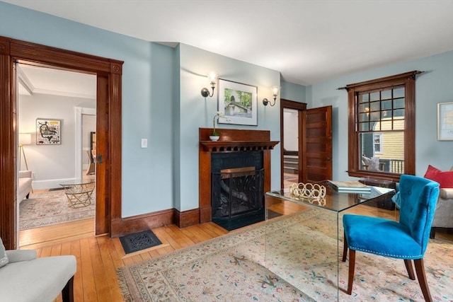 sitting room with a fireplace with flush hearth, hardwood / wood-style floors, and baseboards
