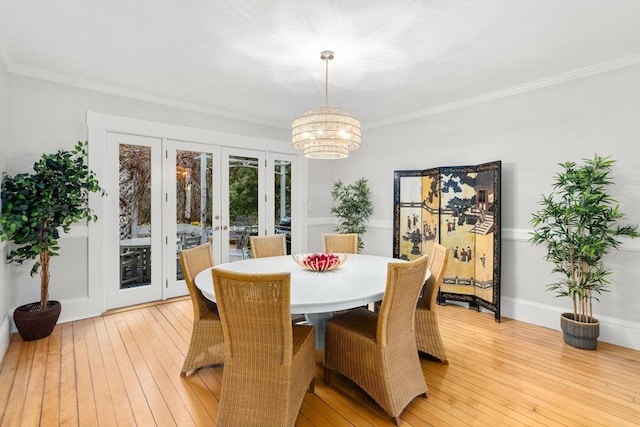 dining area featuring baseboards, an inviting chandelier, french doors, crown molding, and light wood-style floors