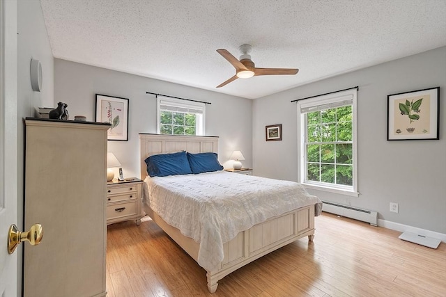 24 Joel Scott Dr, Holden, MA 01520 - bedroom with a baseboard heating unit, multiple windows, a textured ceiling, light wood-style floors, and a ceiling fan