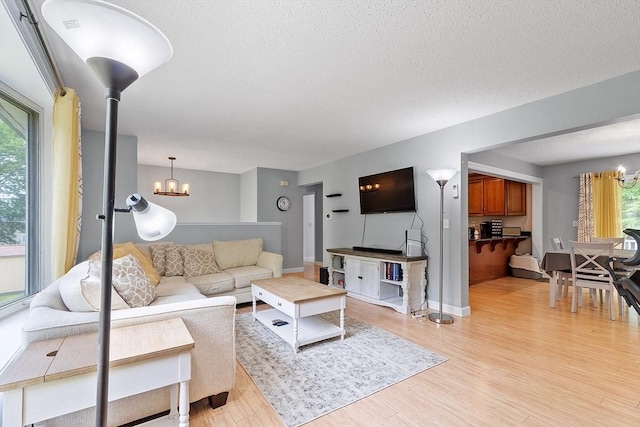 24 Joel Scott Dr, Holden, MA 01520 - living room with a chandelier, light wood-style floors, a textured ceiling, and baseboards