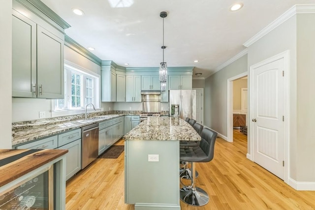 82 Sutton St, Uxbridge, MA 01569 - kitchen with appliances with stainless steel finishes, a breakfast bar area, crown molding, baseboards, and light wood-type flooring