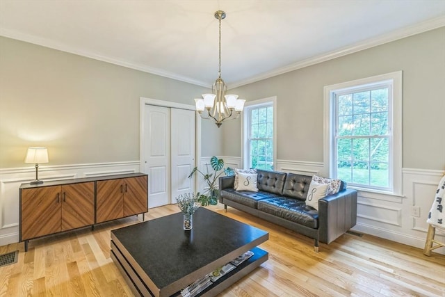 82 Sutton St, Uxbridge, MA 01569 - living room with a chandelier, light wood-style flooring, a wainscoted wall, a decorative wall, and crown molding