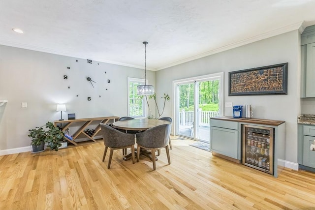 82 Sutton St, Uxbridge, MA 01569 - dining space featuring beverage cooler, light wood-style floors, crown molding, a bar, and baseboards