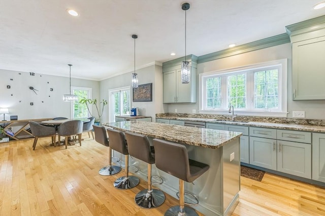 82 Sutton St, Uxbridge, MA 01569 - kitchen with light wood-style floors, plenty of natural light, crown molding, a sink, and light stone counters