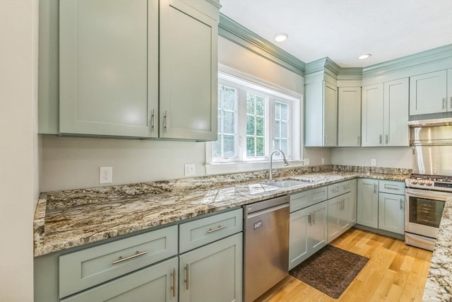 82 Sutton St, Uxbridge, MA 01569 - kitchen with stainless steel appliances, light wood-style flooring, light stone counters, a sink, and under cabinet range hood