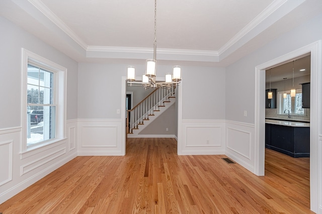 unfurnished dining area featuring crown molding, plenty of natural light, light hardwood / wood-style floors, and a notable chandelier