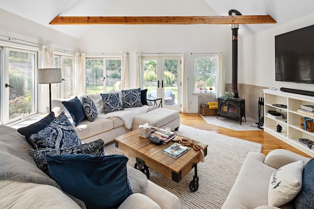 living room with a wood stove, plenty of natural light, and lofted ceiling with beams