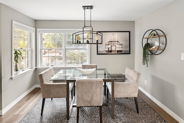 dining space featuring wood-type flooring and an inviting chandelier