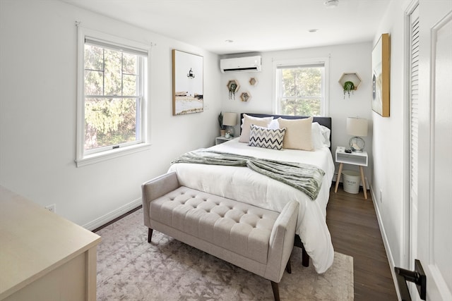 bedroom featuring multiple windows, hardwood / wood-style flooring, and an AC wall unit