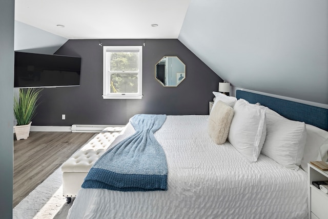 bedroom featuring a baseboard heating unit, vaulted ceiling, and hardwood / wood-style floors