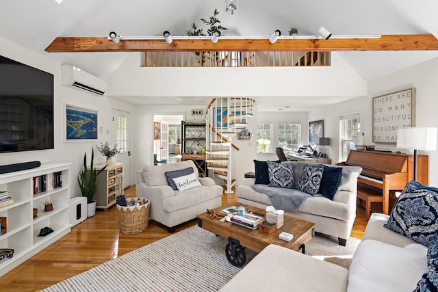 living room featuring beamed ceiling, wood-type flooring, an AC wall unit, and a healthy amount of sunlight