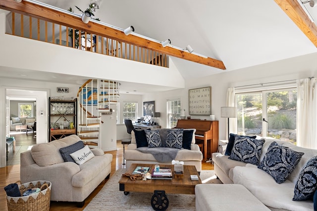 living room with hardwood / wood-style flooring, high vaulted ceiling, a wealth of natural light, and beam ceiling