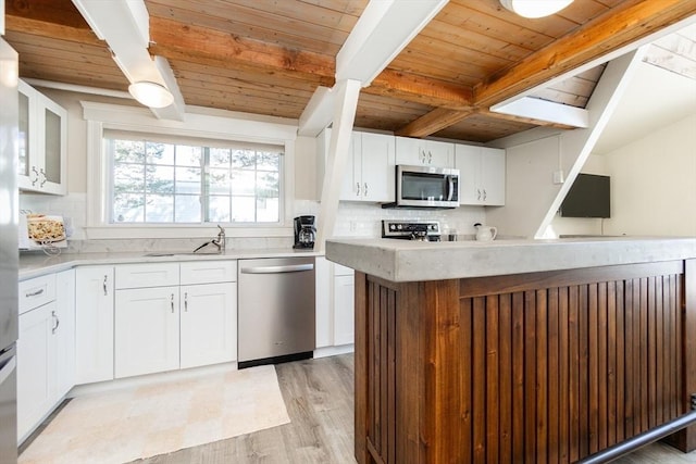 kitchen with beamed ceiling, sink, white cabinets, backsplash, and stainless steel appliances