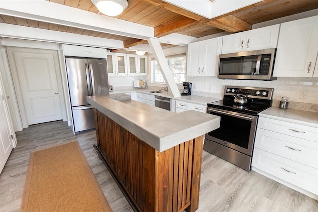 kitchen with tasteful backsplash, a kitchen island, stainless steel appliances, beam ceiling, and white cabinets