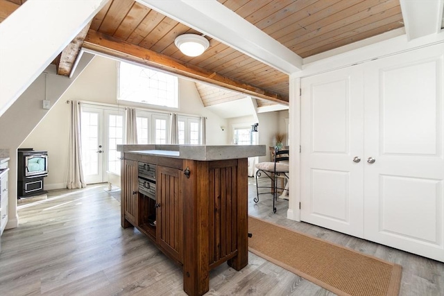 bar with vaulted ceiling with beams, light hardwood / wood-style floors, wooden ceiling, and a wood stove