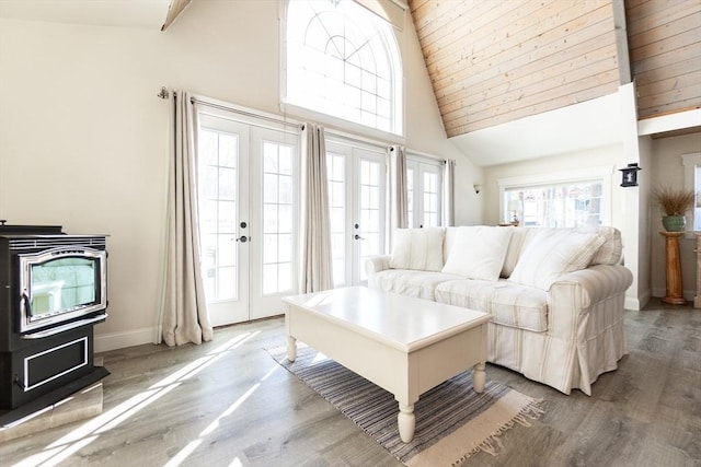 living room with french doors, hardwood / wood-style flooring, high vaulted ceiling, and a wood stove