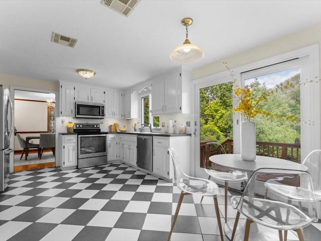 769 Edgell Rd, Framingham, MA 01701 - kitchen with appliances with stainless steel finishes, tile patterned floors, dark countertops, white cabinetry, and pendant lighting